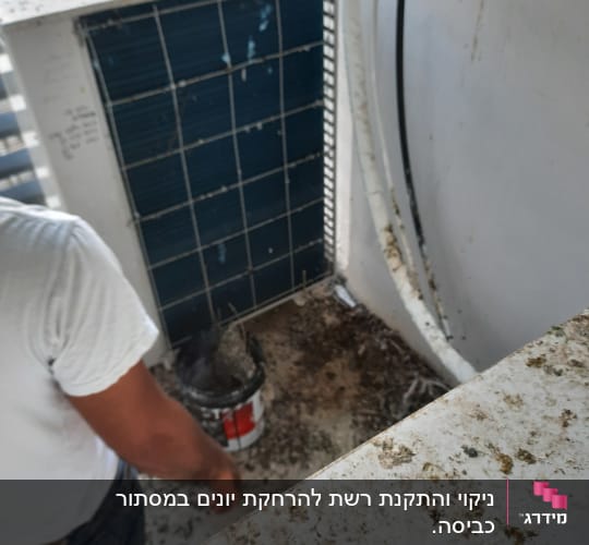אדם מנקה אזור מלוכלך עם דלי ליד מזגן